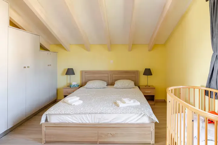 Master bedroom under wooden beams — wake up to soft Aegean light